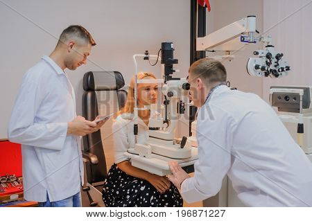 Young Beautiful Two Doctors /eye Specialist/optometrist In An Ophthalmologic Clinic Examines A Woman