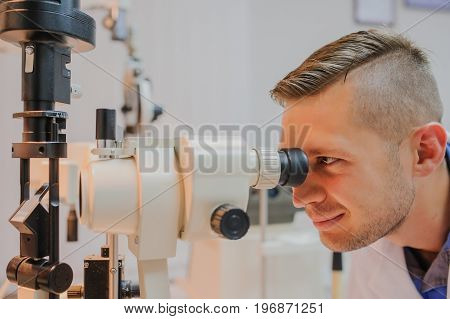 Young beautiful doctor/eye specialist/optometrist in an ophthalmologic clinic test the biomicroscop with slit lamp .