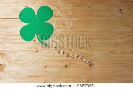 The german words for Good Luck and a cloverleaf on a cord on wood