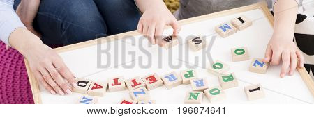 Close-up of young girl setting the word from wooden letters