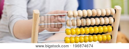 Close-up of young girl with studying problems counting on abacus