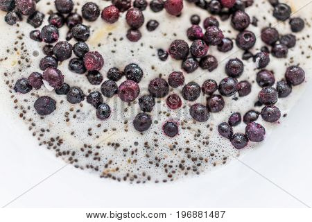 Frozen Blueberries And Chia Seeds Floating On Milk