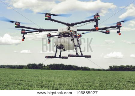 Professional agriculture drone flying and green wheat field, Hovering drone flies in blue sky and taking pictures of green hills.