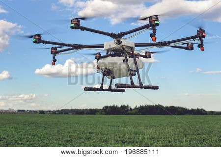 Drone flying above beautiful landscape green field. Hovering drone flies in blue sky and taking pictures of green hills.