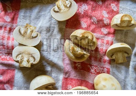 Close up fresh mushrooms cut in halves and old knife lying on cloth for abstract background