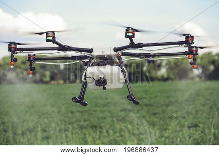 Agriculture drone spraying water or pesticides to grow over green field. Smart farming concept.