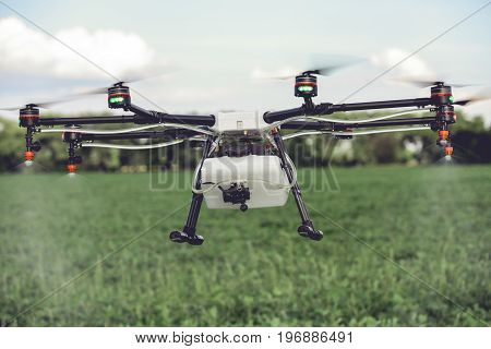 Agriculture drone spraying water or pesticides to grow over green field. Smart farming concept.