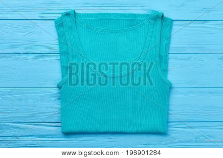 Turquoise t-shirt for sport activity. Single t-shirt isolated on blue wooden bakground.