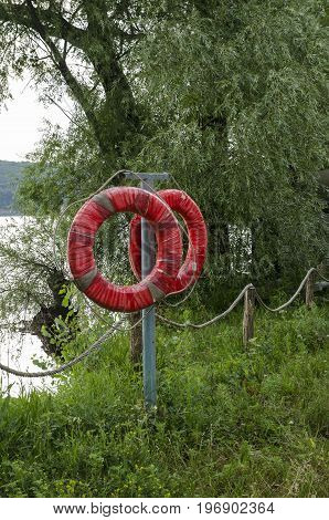 Two red lifebuoys on the river bank