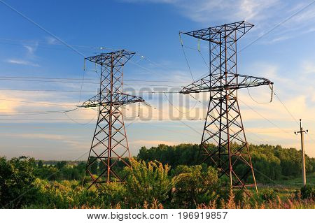 High-voltage power transmission towers in sunset sky background