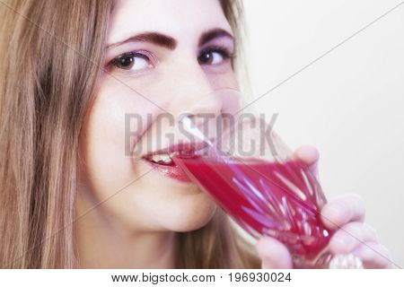 A young girl drinking a red beete juice