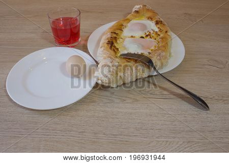 Khachapuri on ajarski - recipe of Georgian cuisine. Adjarian Georgian national dish Khachapuri bread with cheese and egg on a plate in a cafe