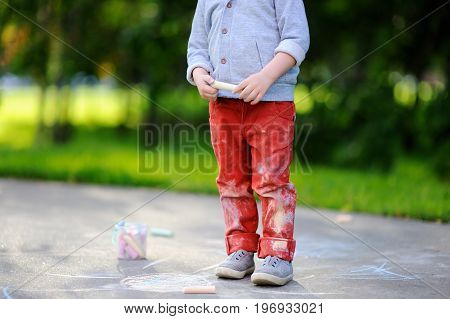 Close-up Photo Of Little Kid Boy Drawing With Colored Chalk On Asphalt.