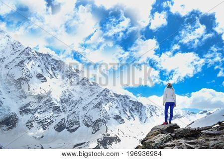 Mountain view.Blonde girl in the mountains. Sky with clouds