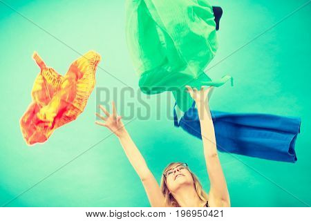 Cleaning in the closet fashion happiness concept. Woman throwing up lot of clothes. Clothing flying all over the place