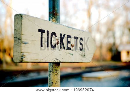 Old wooden sign directing traffic for ticket purchases in a mock railway yard