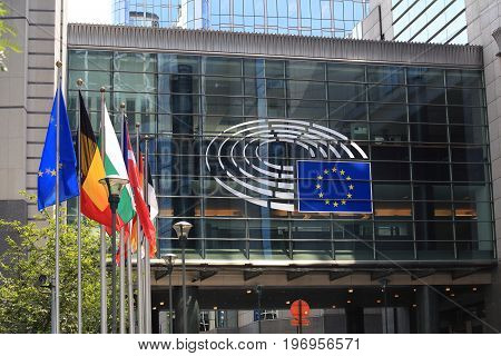 Brussels, Belgium - July 17, 2017: European Parliament building on a sunny day. Emblem of the European Parliament and EU countries flags.