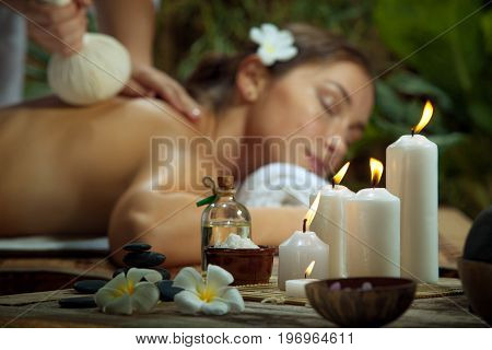 portrait of young beautiful woman in spa environment. focused on candles.