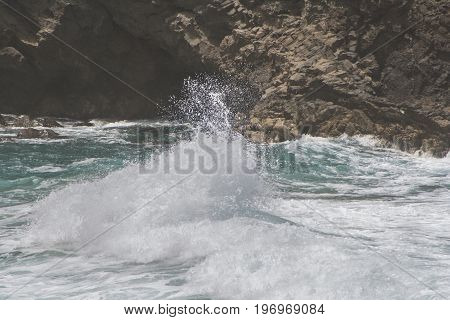 a wave is splashing against a rock close to the shore of the spanish island fuerteventura