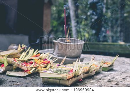 Traditional balinese offerings to gods in Bali with flowers and aromatic sticks. Bali.