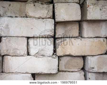 White calcium silicate bricks piled on top of each other. Old, cracked and chipped brick built, rough stack. The texture of the brick close-up.