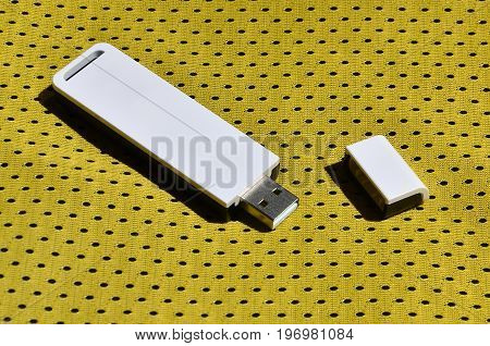 A Modern Portable Usb Wi-fi Adapter Is Placed On The Yellow Sportswear Made Of Polyester Nylon Fiber