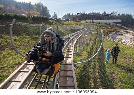 young videographer with gimball video slr at work on alpine coaster