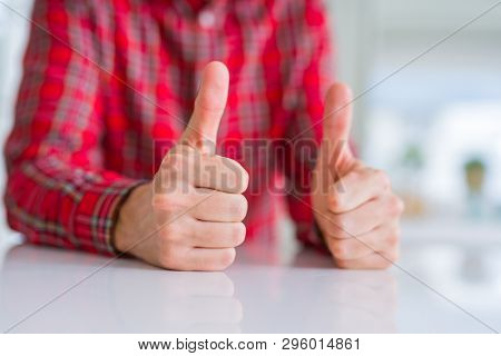 Close up of hands man doing thumbs up gesture over white table