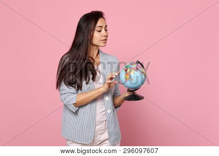 Curious Young Woman In Striped Jacket Holding Pointing Index Finger On Earth World Globe Isolated On