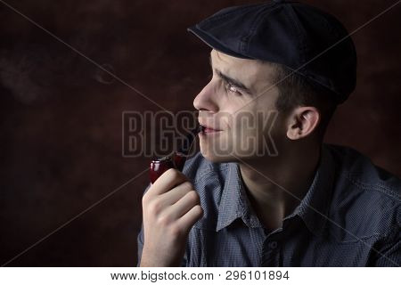 Closeup Portrait Of Young Man With Beret Hat, Smoking A Tobacco Pipe. Thinking About Something. Huma