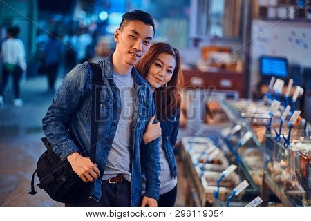 Happy Smiling Asian Couple Is Visiting Chainese Market. They Are Looking To The Camera. A Lot Of Sea