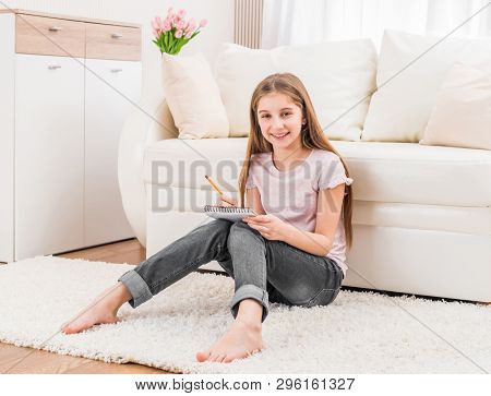 Smiling teenage girl, holding sketchbook doing thumbnails