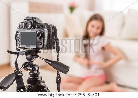 Young smiling videobloger teen girl is pointing at camera in living room