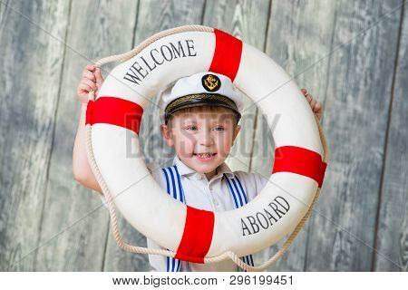 Smiling Boy In Captains Cap Holds In His Hands A Lifebuoy