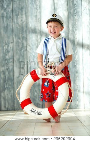 Smiling Boy In Captains Cap Holds In His Hands A Lifebuoy