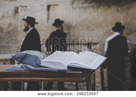 Jewish Bible - Torrah Open On Table On Blurred Background Of Praying Jews And Wailing Western Wall. 