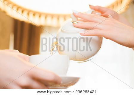 Tea Party. Women Pour Green Tea Into A White Cup