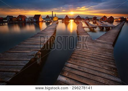 Sunset over lake Bokod with wooden pier and floating houses, power plant in background, Hungary