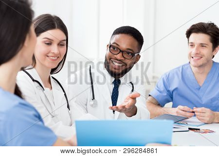Multiracial Medical Team Having Meeting With Doctor, Discussing Patients Records