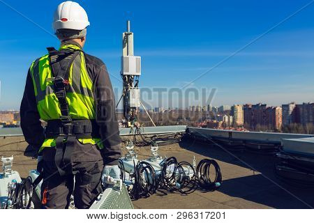 Professional Industrial Climber In Helmet And Uniform With Telecomunication Equipment In His Hand An