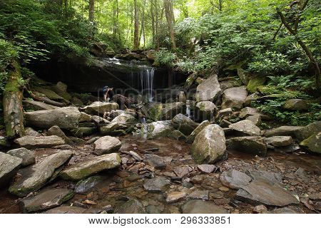 Young Woman Explores A Small Trailside Waterfall In The Great Smoky Mountains National Park, Tenness
