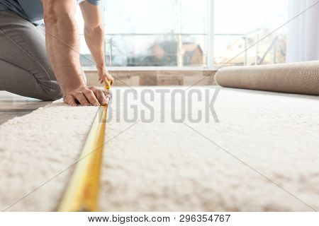 Man Measuring Carpet Indoors. Construction Tool Closeup
