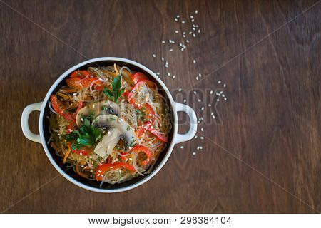 Glass Noodles With Vegetables And Mushrooms In A Plate On A Brown Background. Top View, Close-up, Co