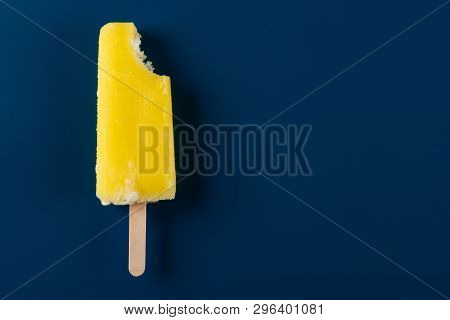 Yellow Popsicle With A Bite On A Navy Blue Background