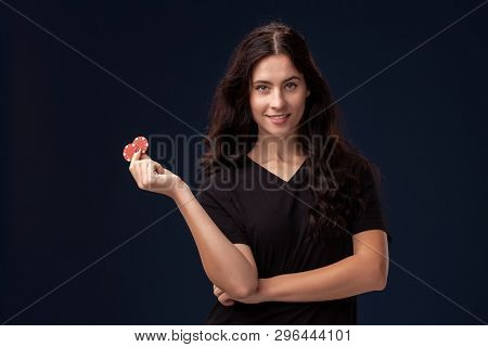 Curly Hair Brunette Is Posing With Red Gambling Chips In Her Hands. Poker Concept On A Black Backgro