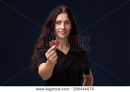 Curly Hair Brunette Is Posing With Red Gambling Chips In Her Hands. Poker Concept On A Black Backgro
