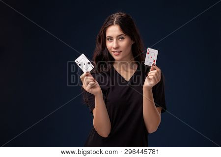 Curly Hair Brunette Is Posing With Playing Cards In Her Hands. Poker Concept On A Black Background. 