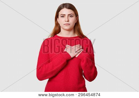 Calm Dark Haired Female With Serious Facial Expression, Keeps Both Palms On Heart, Being Touched By 
