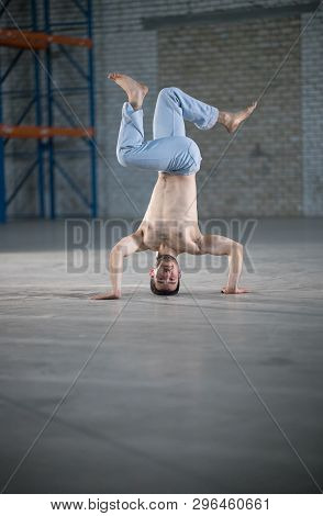 An Athletic Man On Capoeira Training. Standing On The Hands In The Pose
