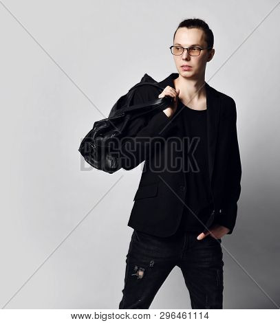 Stylish Man With A Bun On Head In Glasses, Black Jeans, T-shirt And With A Big Stylish Bag On His Sh
